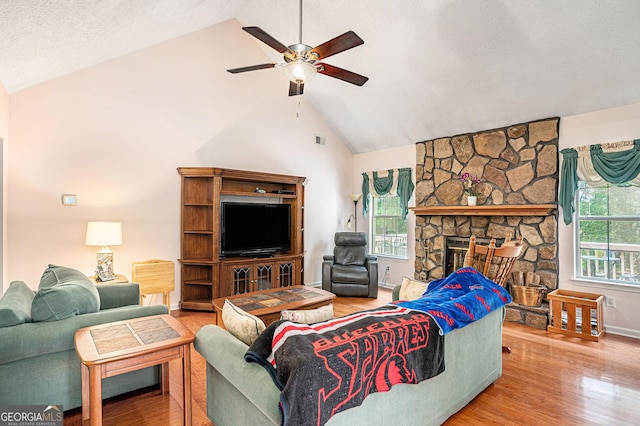 living area with a ceiling fan, a fireplace, wood finished floors, high vaulted ceiling, and baseboards