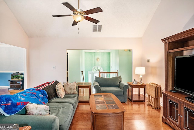 living area featuring visible vents, a ceiling fan, lofted ceiling, and light wood-type flooring