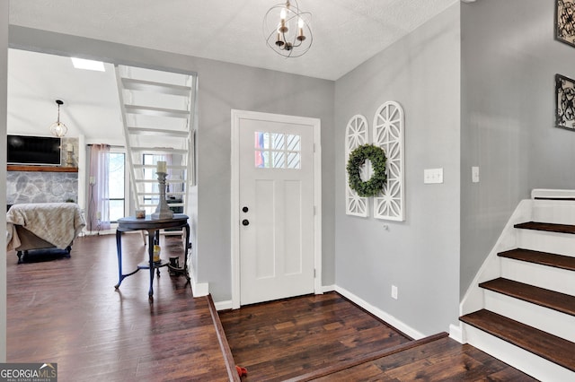 foyer entrance with plenty of natural light, dark wood finished floors, a chandelier, and stairway