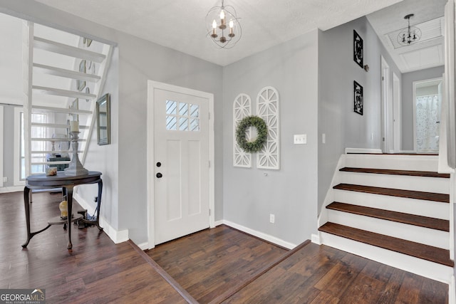 entrance foyer featuring dark wood-style flooring, a chandelier, and baseboards