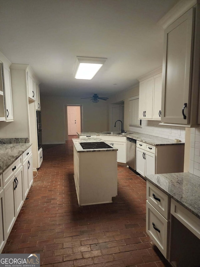kitchen featuring black appliances, light stone countertops, a peninsula, and tasteful backsplash