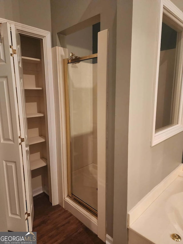 bathroom featuring wood finished floors, vanity, and a stall shower