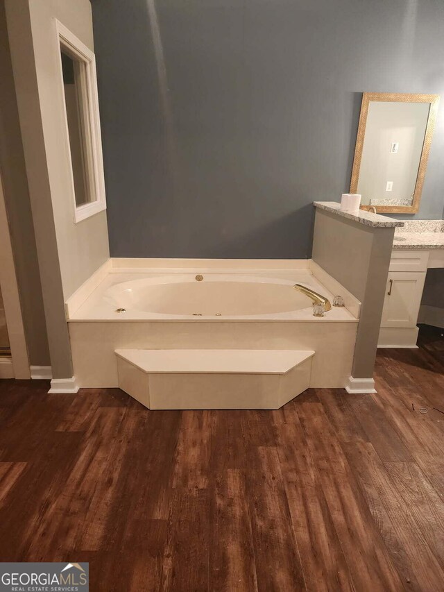 bathroom with a bath, wood finished floors, and vanity