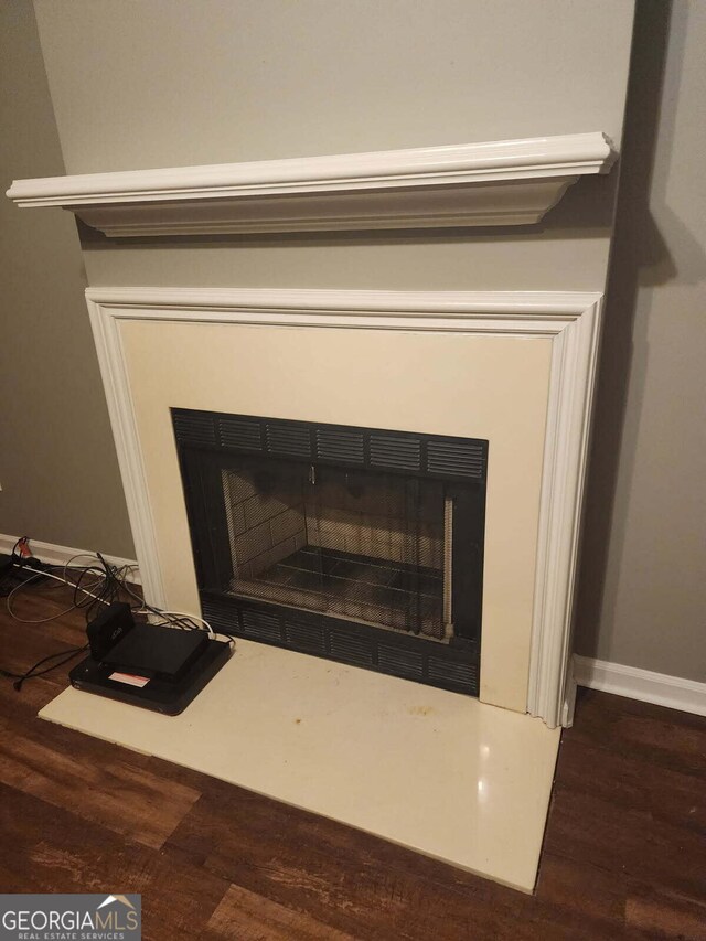 details featuring a fireplace with flush hearth, wood finished floors, and baseboards