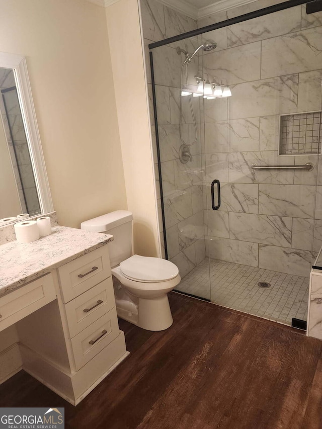 bathroom featuring a shower stall, crown molding, toilet, wood finished floors, and vanity