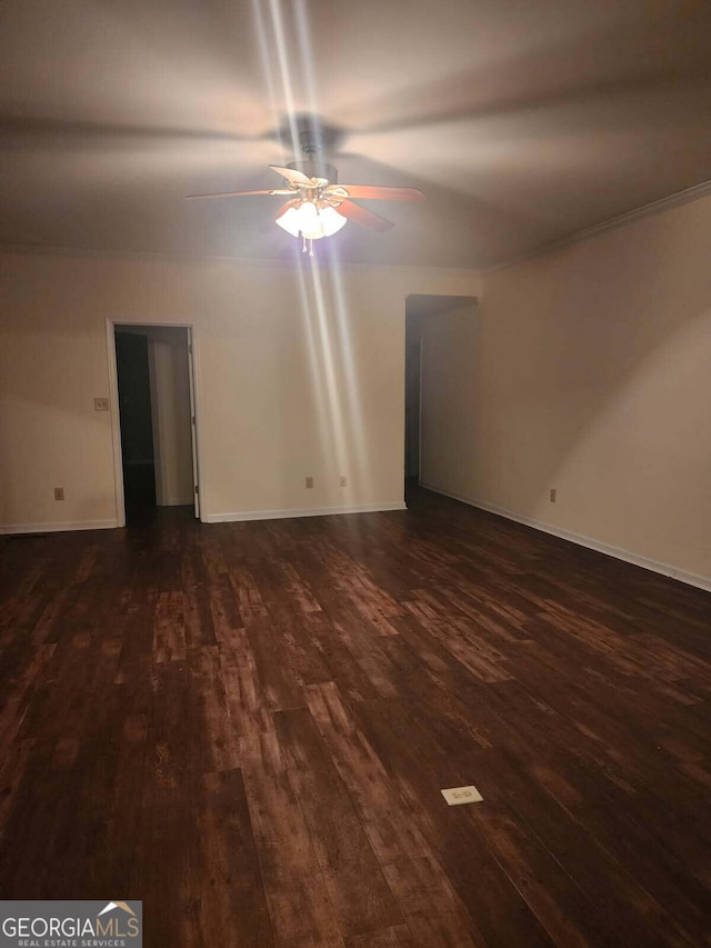 unfurnished room with dark wood-style flooring, a ceiling fan, and baseboards
