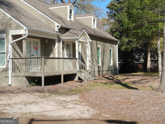 view of side of property with covered porch and a shingled roof