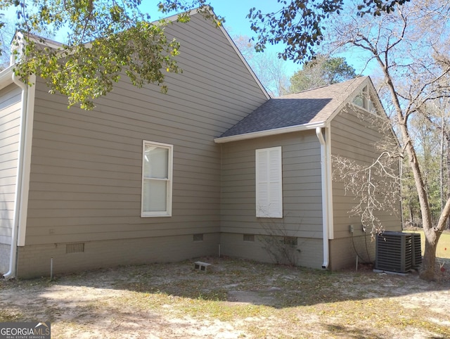 view of side of home with roof with shingles, central AC, and crawl space