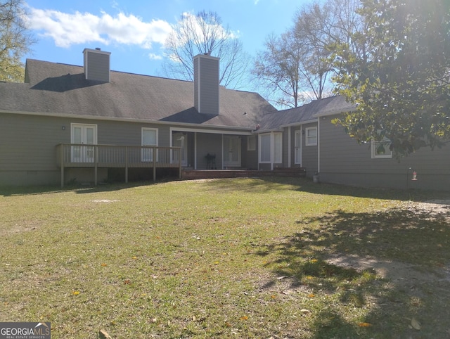 back of property featuring a lawn, a sunroom, and a chimney