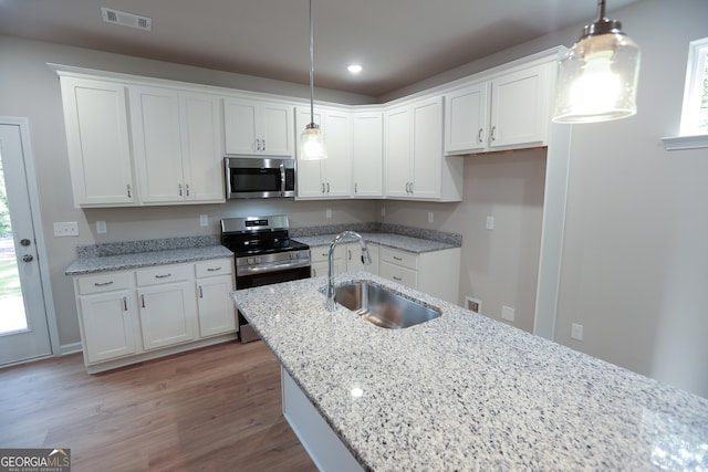 113 Sharp St, Bremen, GA 30110 - kitchen featuring appliances with stainless steel finishes, a sink, white cabinets, light wood-style floors, and light stone counters