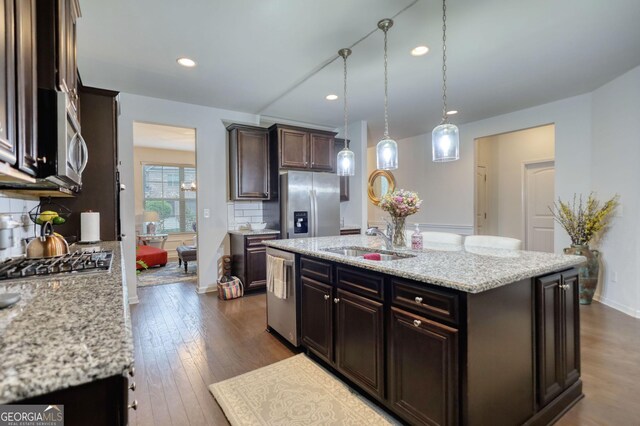 164 Madison Grace Ave, Mcdonough, GA 30252 - kitchen with light stone counters, dark brown cabinetry, a sink, appliances with stainless steel finishes, and decorative backsplash