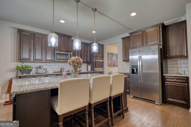 164 Madison Grace Ave, Mcdonough, GA 30252 - kitchen with a breakfast bar, dark brown cabinets, appliances with stainless steel finishes, and light wood finished floors
