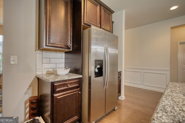 164 Madison Grace Ave, Mcdonough, GA 30252 - kitchen with light stone countertops, light wood-style floors, stainless steel fridge with ice dispenser, backsplash, and wainscoting