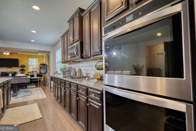 164 Madison Grace Ave, Mcdonough, GA 30252 - kitchen featuring dark brown cabinets, light wood-style floors, decorative backsplash, and stainless steel appliances