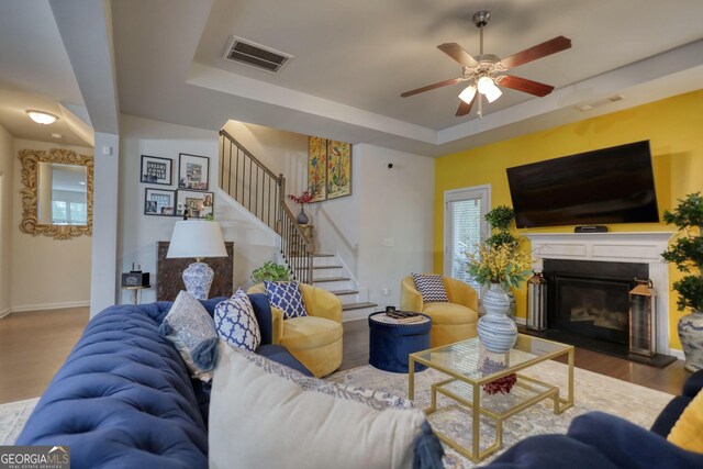 164 Madison Grace Ave, Mcdonough, GA 30252 - living room featuring a tray ceiling, stairs, a ceiling fan, wood finished floors, and visible vents