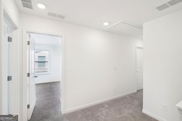 unfurnished room featuring attic access, visible vents, and carpet floors