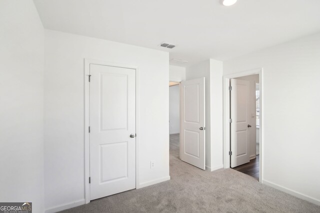 unfurnished bedroom with carpet, baseboards, and visible vents