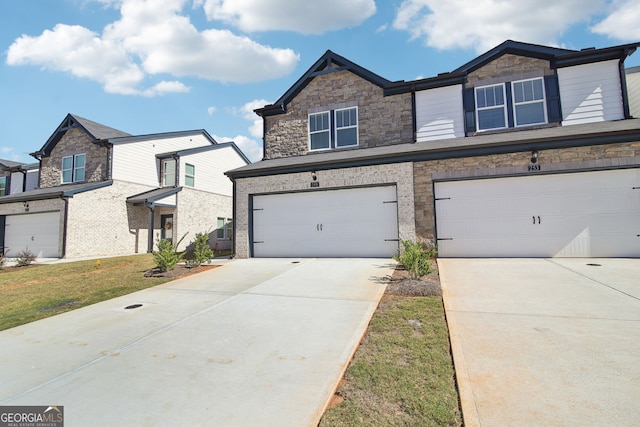 view of front of house featuring driveway, an attached garage, and stone siding