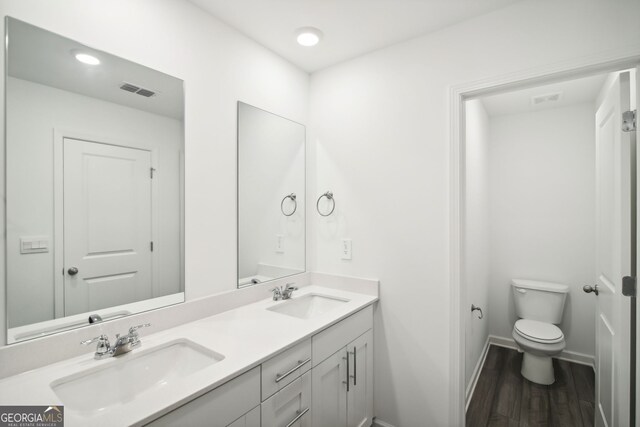 full bath featuring double vanity, visible vents, a sink, and toilet