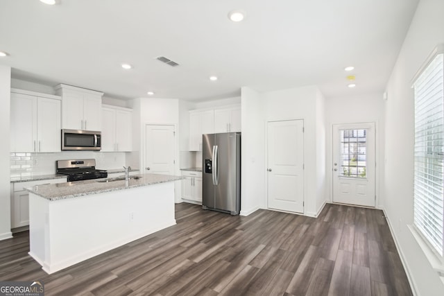 kitchen featuring visible vents, stainless steel appliances, a sink, dark wood-style floors, and backsplash