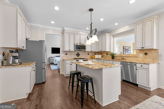kitchen with crown molding, a kitchen island, a breakfast bar area, stainless steel appliances, and dark wood-type flooring