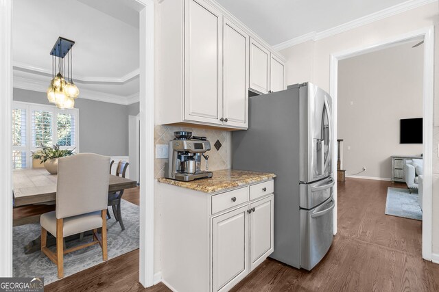 kitchen with crown molding, backsplash, white cabinetry, stainless steel fridge, and dark wood-style flooring