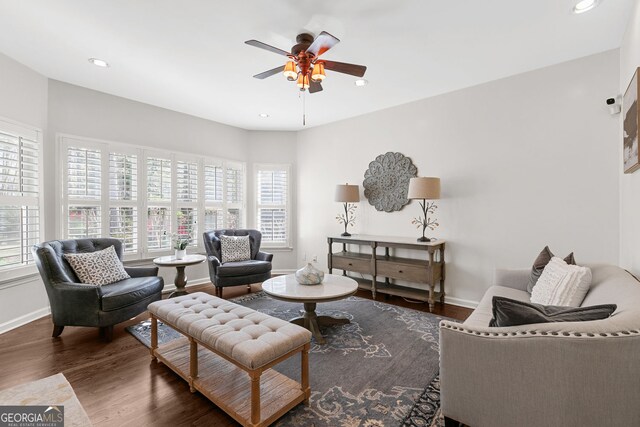 living room featuring baseboards, wood finished floors, a ceiling fan, and plenty of natural light