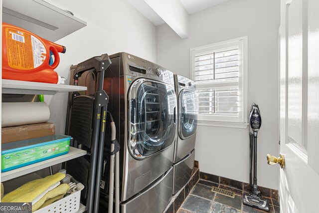 washroom featuring baseboards, stone finish floor, independent washer and dryer, and laundry area