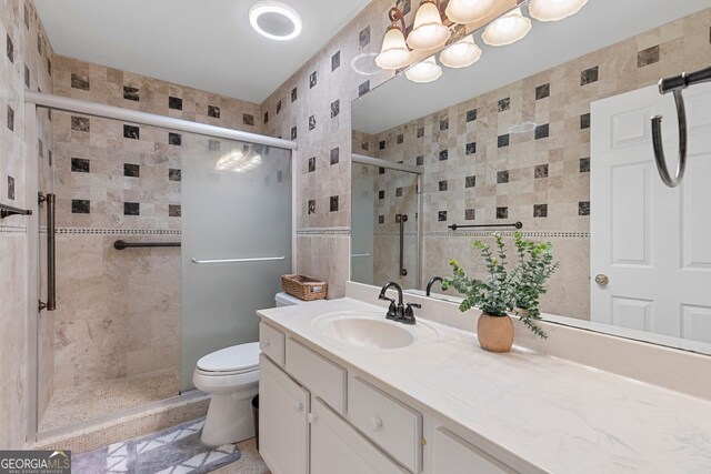full bathroom featuring toilet, vanity, tile walls, and a shower stall