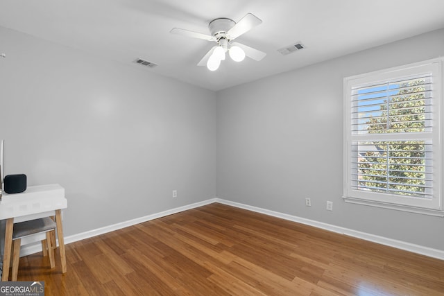 empty room with baseboards, visible vents, wood finished floors, and ceiling fan