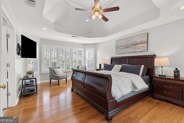bedroom with visible vents, light wood-style flooring, recessed lighting, and a raised ceiling