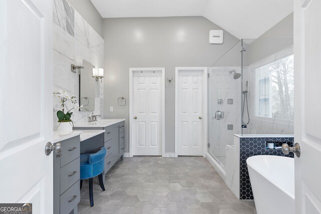 full bathroom featuring lofted ceiling, a stall shower, vanity, and a freestanding bath