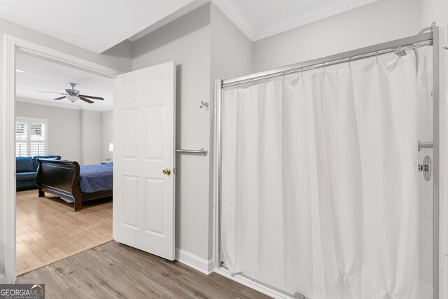 bathroom with ornamental molding, baseboards, ceiling fan, curtained shower, and wood finished floors