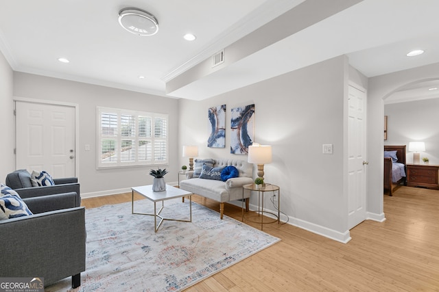 living area with visible vents, wood finished floors, arched walkways, and ornamental molding