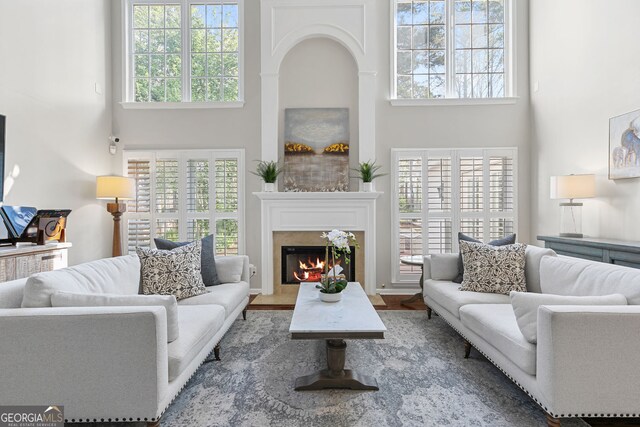 living room with a fireplace with flush hearth and a high ceiling