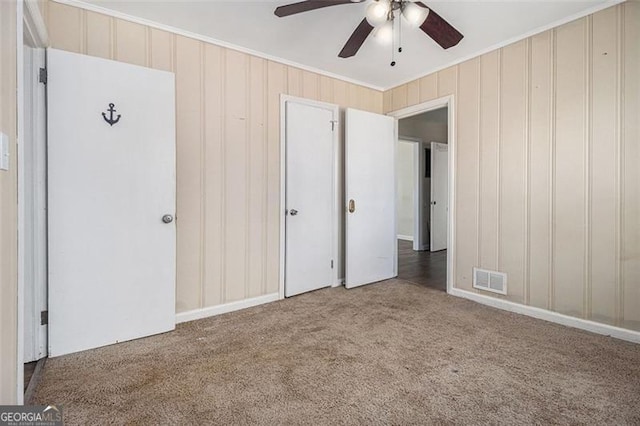 unfurnished bedroom with visible vents, ceiling fan, carpet floors, and ornamental molding