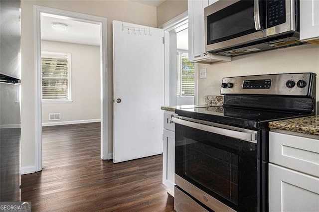kitchen featuring stainless steel appliances, dark wood-type flooring, dark stone countertops, visible vents, and white cabinets