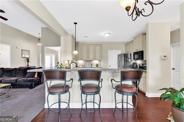 95 Summerlyn Dr, Hiram, GA 30141 - kitchen with cream cabinetry, black microwave, open floor plan, freestanding refrigerator, and a breakfast bar