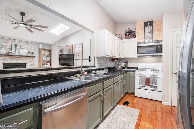 90 Chimney Rise Ct, Stockbridge, GA 30281 - kitchen with stainless steel appliances, a sink, dark countertops, light wood-style floors, and a ceiling fan