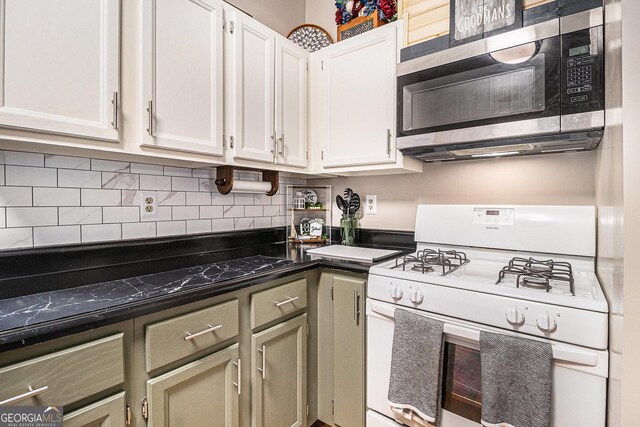 90 Chimney Rise Ct, Stockbridge, GA 30281 - kitchen featuring white gas range oven, stainless steel microwave, dark countertops, tasteful backsplash, and white cabinets