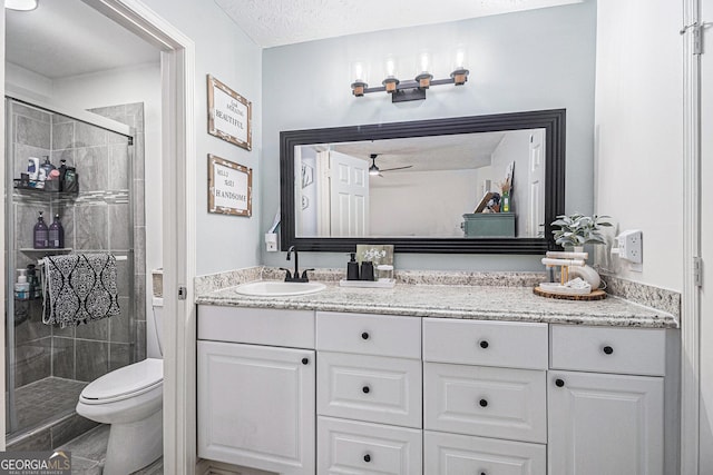 full bath featuring vanity, toilet, a textured ceiling, a shower stall, and a ceiling fan