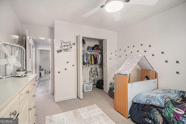 bedroom featuring attic access, light colored carpet, a closet, and ceiling fan
