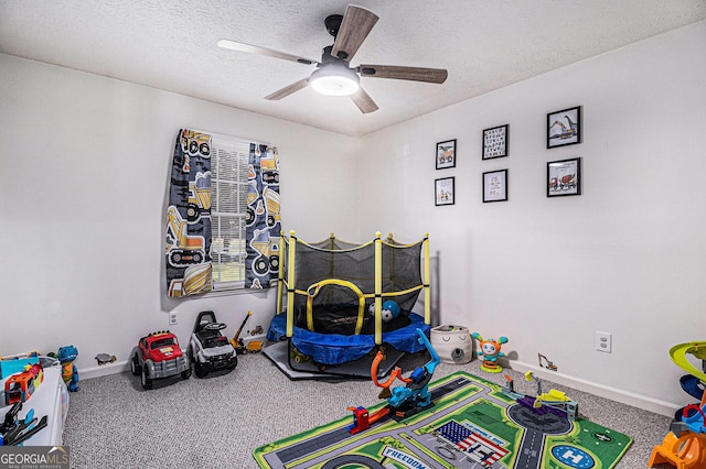 game room with carpet, baseboards, ceiling fan, and a textured ceiling