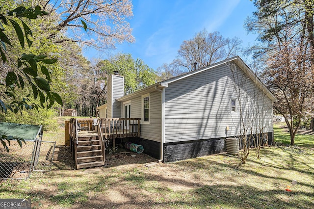 view of side of property with a chimney, a gate, and a deck