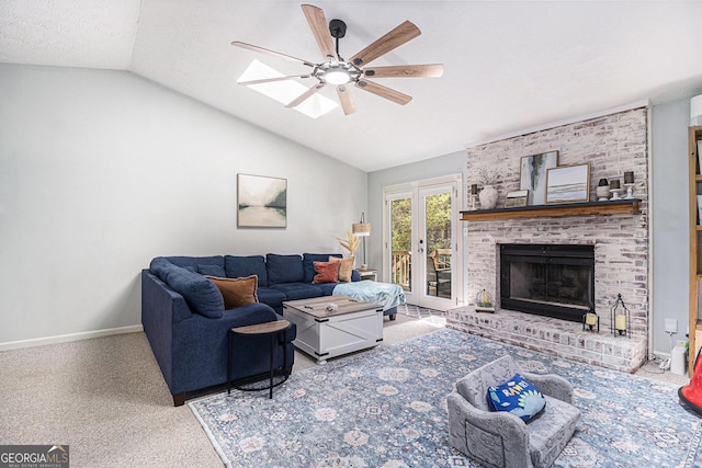 carpeted living room featuring a textured ceiling, a brick fireplace, baseboards, vaulted ceiling with skylight, and a ceiling fan