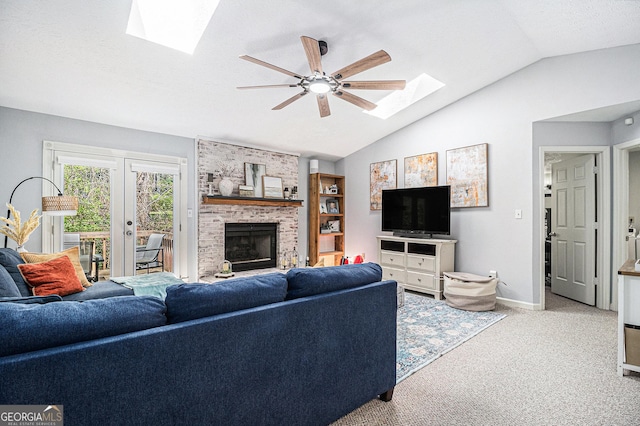 carpeted living room with vaulted ceiling with skylight, a fireplace, a textured ceiling, baseboards, and ceiling fan