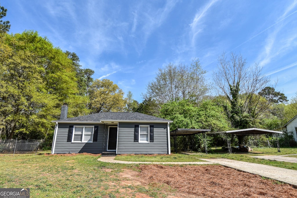 view of front of house with fence, a chimney, concrete driveway, a front yard, and a carport