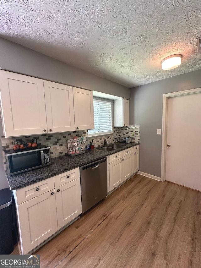 2900 Haddon Dr, Rex, GA 30273 - kitchen featuring appliances with stainless steel finishes, light wood-type flooring, tasteful backsplash, white cabinetry, and a textured ceiling