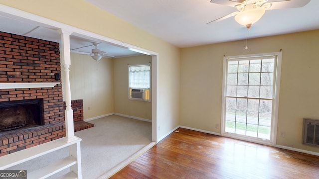 unfurnished living room with plenty of natural light, ceiling fan, cooling unit, and wood finished floors