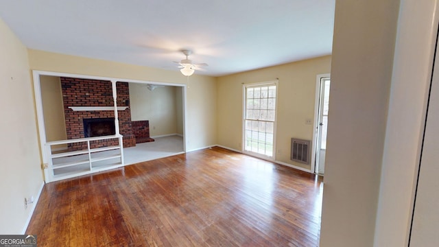 unfurnished living room with a fireplace, a ceiling fan, baseboards, wood finished floors, and visible vents